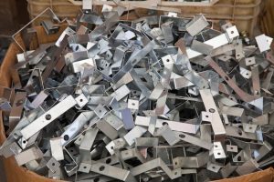 A cardboard box filled with stainless steel scrap metal brackets